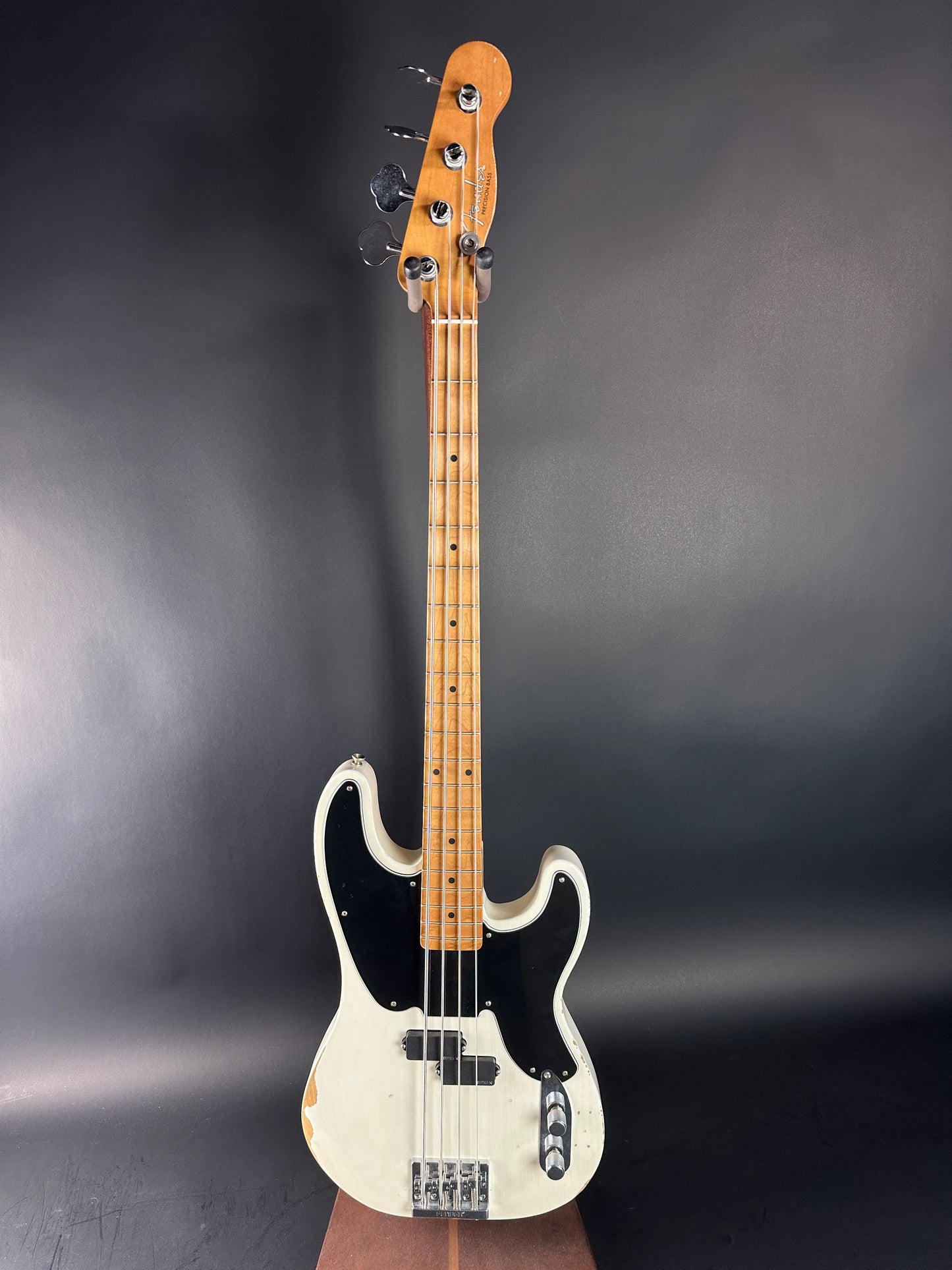 Electric bass guitar with a white pickguard on a dark gray background