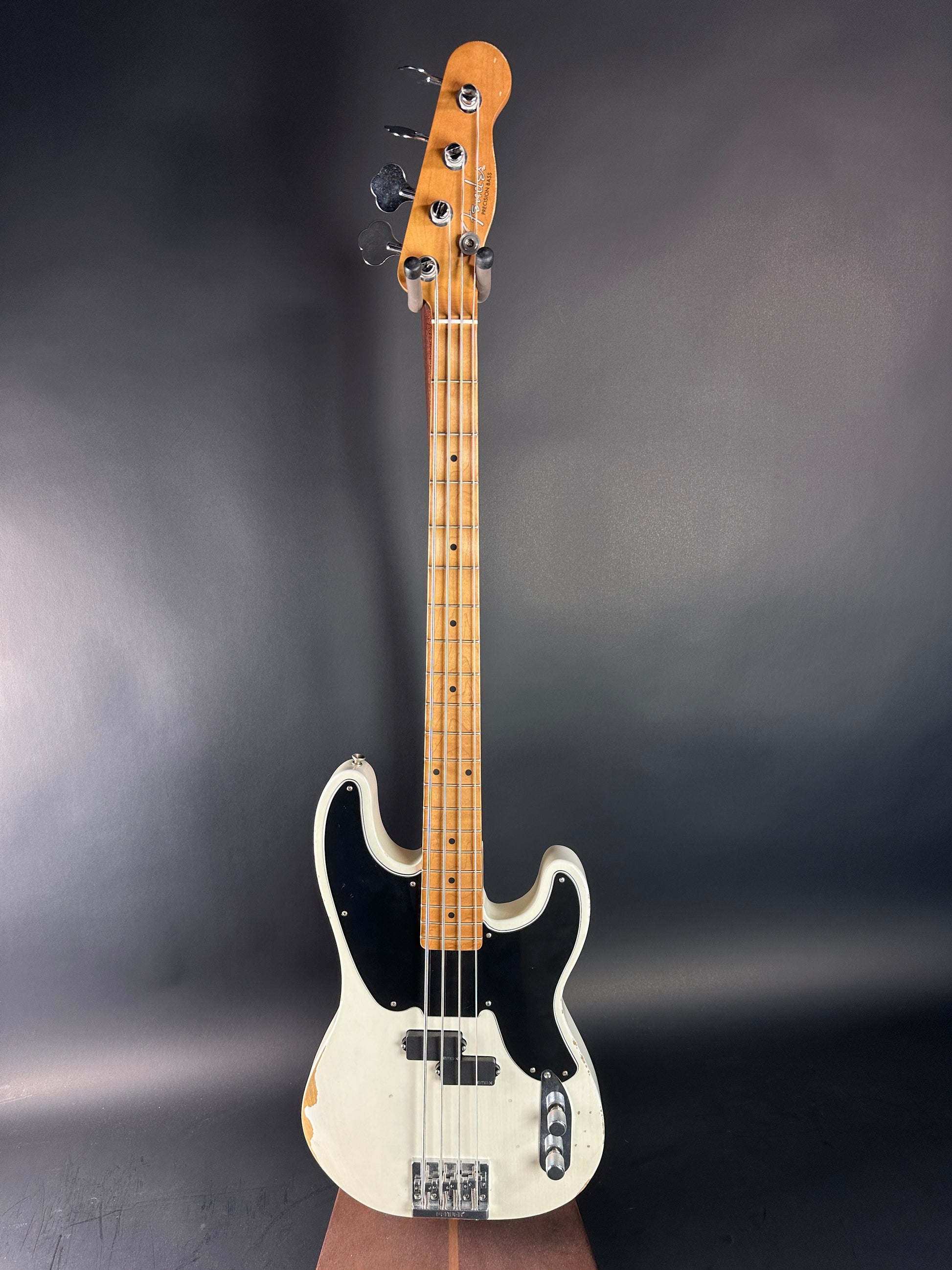 Electric bass guitar with a white pickguard on a dark gray background