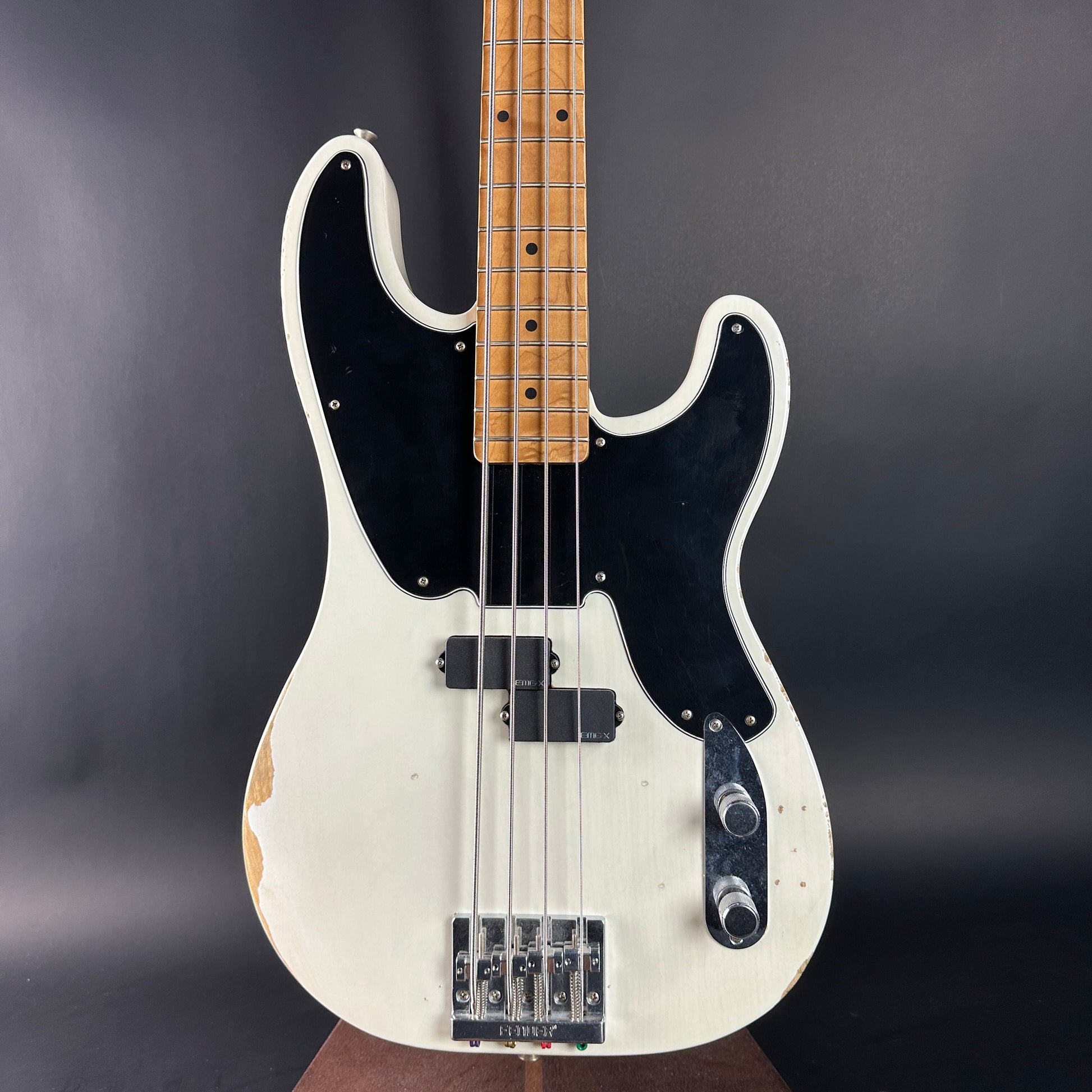 White electric bass guitar with a black pickguard on a dark gray background