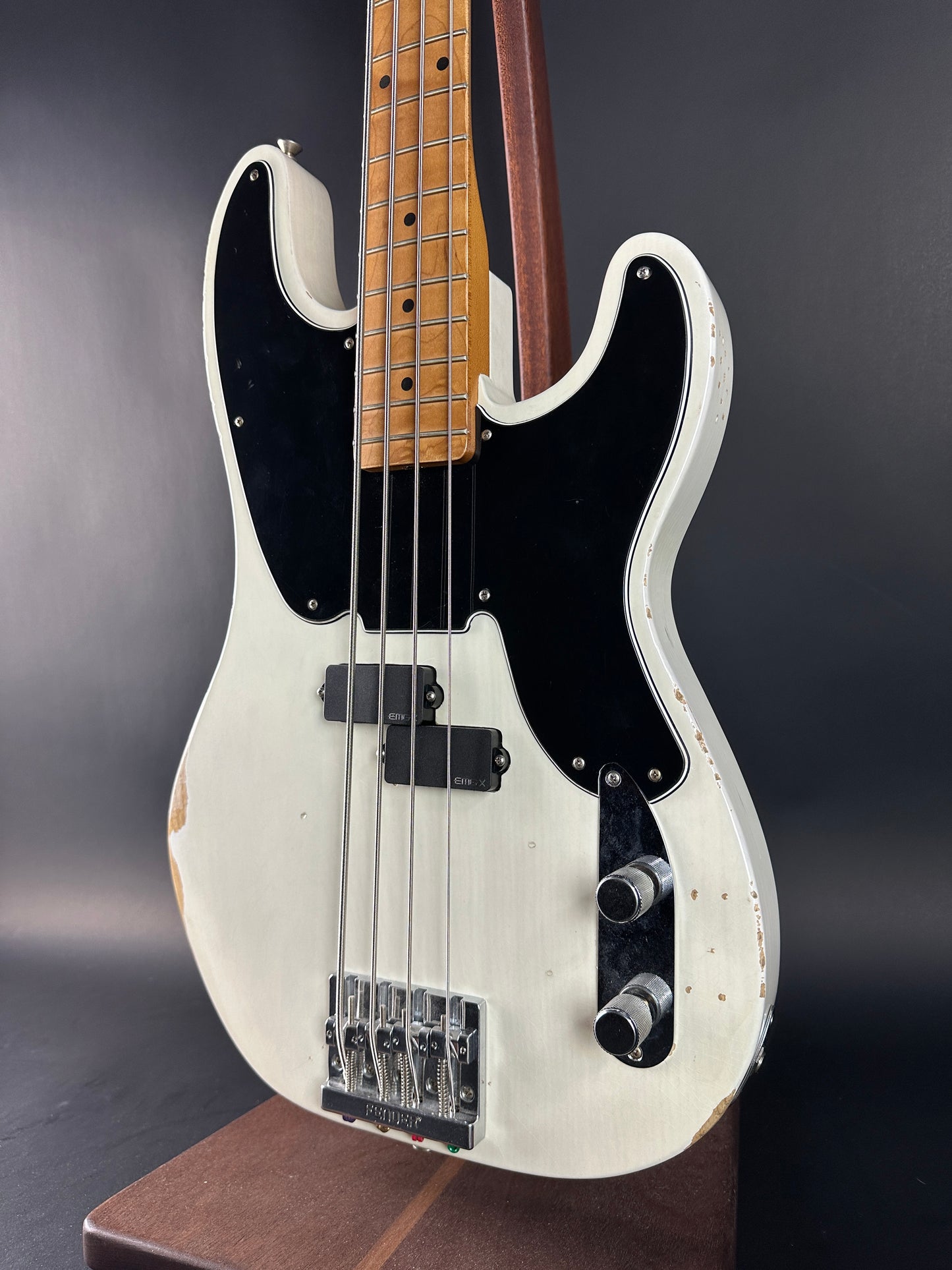 White electric bass guitar with black pickguard on a dark background