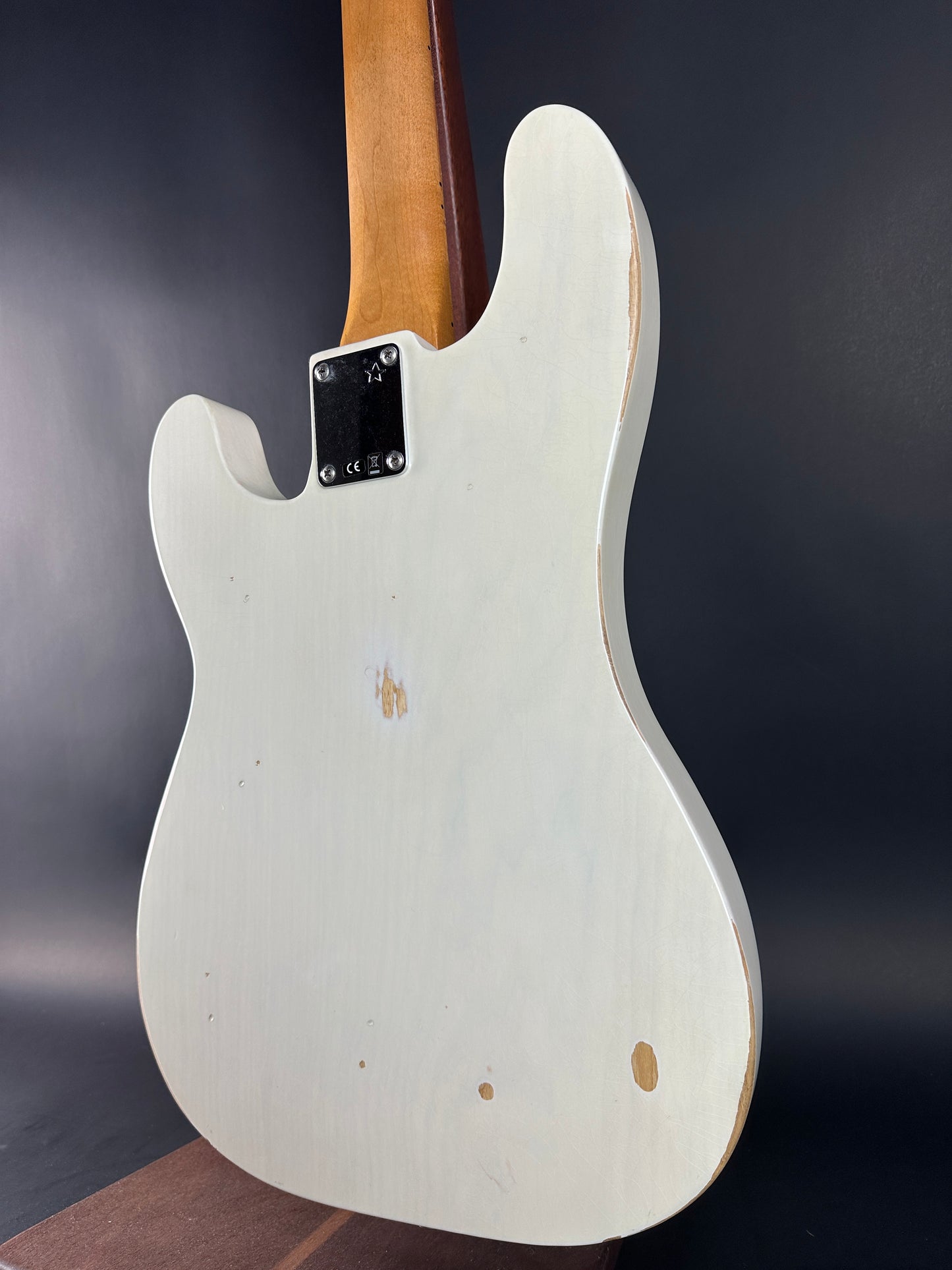 White electric guitar body with visible brand logo on a dark background