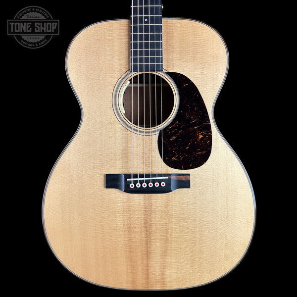 A front-facing acoustic guitar with a natural flamed maple top, dark fretboard, and dark tortoiseshell pickguard, shown against a solid black background. A Tone Shop watermark is visible in the top-left corner.