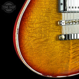 Close-up of a sunburst electric guitar with a visible brand logo in the corner.