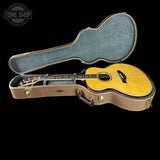 Acoustic guitar in an open case with 'Tone Shop' logo.