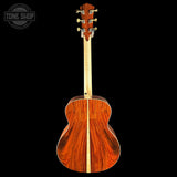 Back view of a wooden acoustic guitar on a black background with 'Tone Shop' logo.