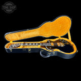 Guitar in an open hardshell case with 'Tone Shop' logo in the corner.