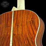 Close-up of a wooden acoustic guitar with 'Tone Shop' branding.
