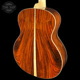 Close-up of a wooden acoustic guitar on a black background with 'Tone Shop' logo.