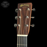 Close-up of the headstock of a Martin & Co acoustic guitar against a black background, showing the dark wood grain, gold lettering, and silver tuning keys. A Tone Shop watermark is visible in the top left corner.