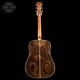 The back of an acoustic guitar with a rich, dark brown wood grain pattern, shown against a solid black background with a Tone Shop watermark in the top left corner.