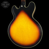 Close-up of a guitar's back with a gradient finish on a black background, featuring the 'Tone Shop' logo.