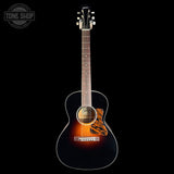 A Taylor acoustic guitar with a glossy black finish and a classic sunburst finish on the body, featuring a tiger-stripe style pickguard, set against a solid black background.