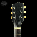 Close-up of a guitar headstock with tuning pegs on a black background, featuring 'Tone Shop' branding.