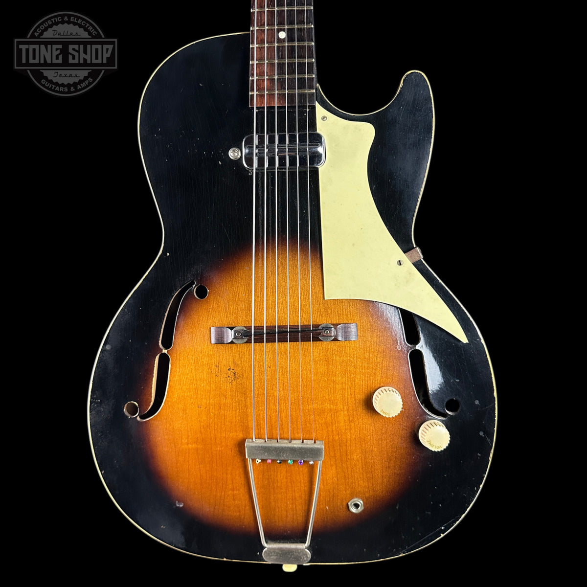 Vintage-style electric guitar with a black and brown design on a black background, featuring the Tone Shop logo.