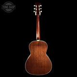 The back of an acoustic guitar with a rich reddish-brown wood finish, shown from a rear three-quarter angle against a solid black background. A Tone Shop watermark is visible in the top-left corner.