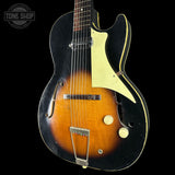 Vintage-style electric guitar with a black and brown design on a black background, featuring 'Tone Shop' branding.