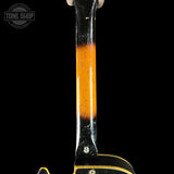 Close-up of a guitar neck with a black and orange color scheme on a black background, featuring 'Tone Shop' branding.