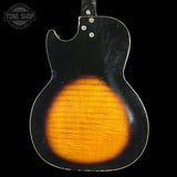 Back view of a vintage electric guitar with a sunburst finish on a black background.