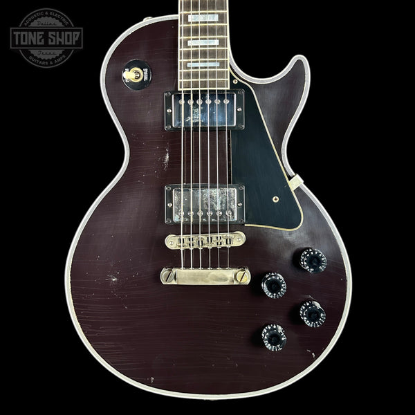 Electric guitar with a dark finish on a black background, featuring the 'Tone Shop' logo.