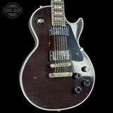 Electric guitar with a dark finish on a black background, featuring the 'Tone Shop' logo.