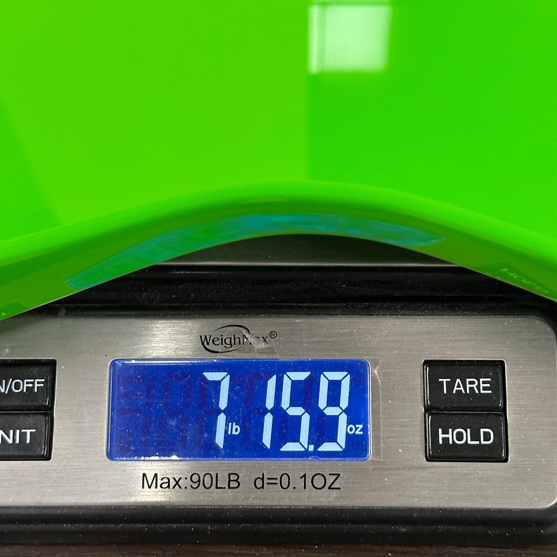 Digital scale displaying weight with a green object partially visible