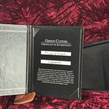 Gibson Custom Certificate of Authenticity on a red textured surface