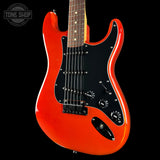 A classic electric guitar with a vibrant orange-red body, black pickguard, and maple neck, shown against a solid black background with a Tone Shop watermark in the top left corner.