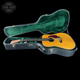 Acoustic guitar in a green-lined case with 'Tone Shop' logo.