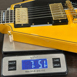 Yellow electric guitar on a digital scale displaying weight.