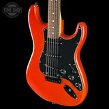A bright orange electric guitar with a black pickguard and maple neck, shown against a solid black background with a Tone Shop watermark in the top-left corner.