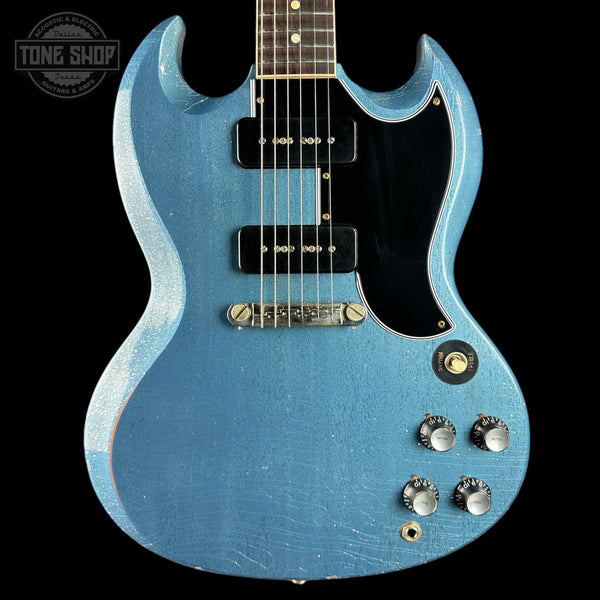 Blue electric guitar with a black pickguard on a dark background, featuring the 'Tone Shop' logo.