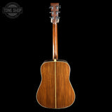 Back view of a wooden acoustic guitar on a black background with 'Tone Shop' logo.