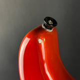 Close-up of a glossy red curved object with a black top cap against a dark gray background.