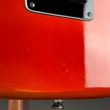 Close-up detail of a red electric guitar body showing a black pickguard with silver screws and a glossy finish.
