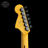 Close-up of the headstock of a Fender electric guitar in a natural maple finish, showing the six tuning pegs and brand name printed on the back, set against a solid black background.