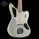 A silver glitter electric guitar with a white pickguard and black control plates, shown against a solid black background with a Tone Shop logo in the top left corner.