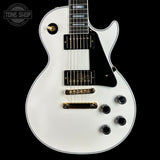 White electric guitar with a black pickguard on a black background, featuring the 'Tone Shop' logo.