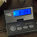 A smart weigh digital scale displaying '8.29 kg' on a blue backlit screen, resting on a dark wooden surface.