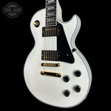 White electric guitar with gold hardware on a black background, featuring 'Tone Shop' logo.