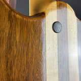 Close-up of a guitar body showing a dark brown wood grain section next to a lighter natural wood veneer stripe with a small dark circular hardware detail.