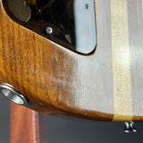 Close-up of a wooden electric guitar body showing the wood grain, a silver metal pickguard, and hardware screws.