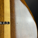 Close-up detail of a wooden instrument body showing a dark brown wood veneer, a light natural wood stripe, and a glossy silver-finished section with four metal hardware mounts.