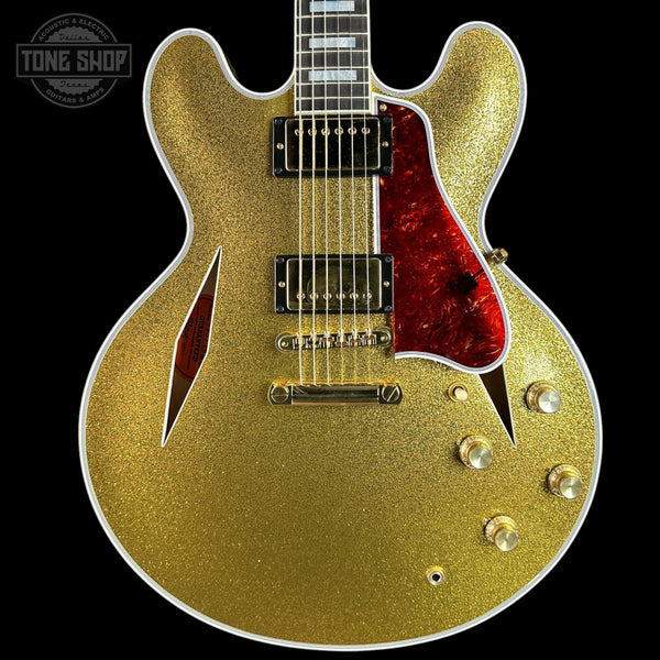 Gold glitter electric guitar with red pickguard on a black background