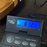 A close-up of a smart weigh ACE110 digital scale with a blue backlit LCD screen showing '8.12.
