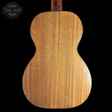 Back view of a wooden acoustic guitar with 'Tone Shop' logo in the corner.