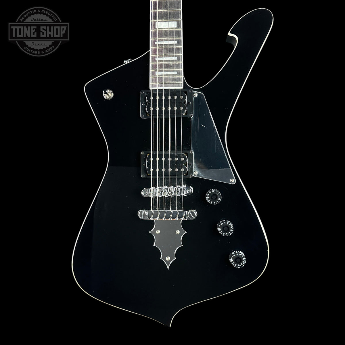 A black electric guitar with a glossy finish, chrome hardware, and a dark fretboard, shown against a solid black background with a Tone Shop watermark in the top-left corner.
