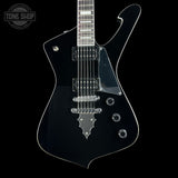 A black electric guitar with a glossy finish, chrome hardware, and a dark fretboard, shown against a solid black background with a Tone Shop watermark in the top-left corner.
