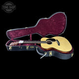 Acoustic guitar in an open case with 'Tone Shop' branding.