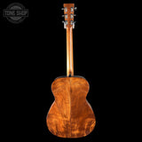 Back view of a wooden acoustic guitar on a black background with 'Tone Shop' logo.