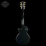 A black electric guitar shown from the back against a solid black background, with a Tone Shop watermark in the upper left corner.